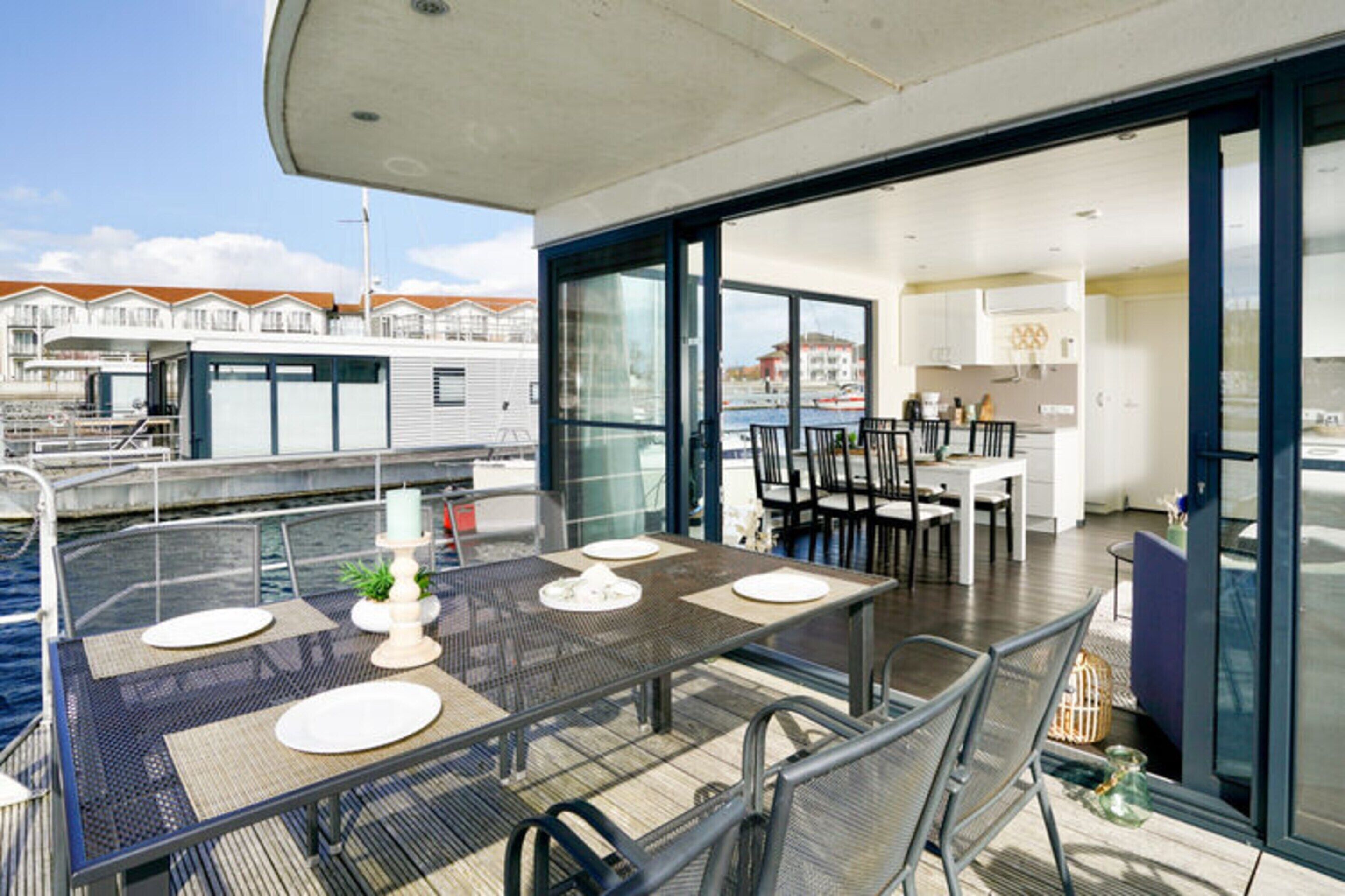 A modern outdoor dining area with a table set for four, overlooking the water.