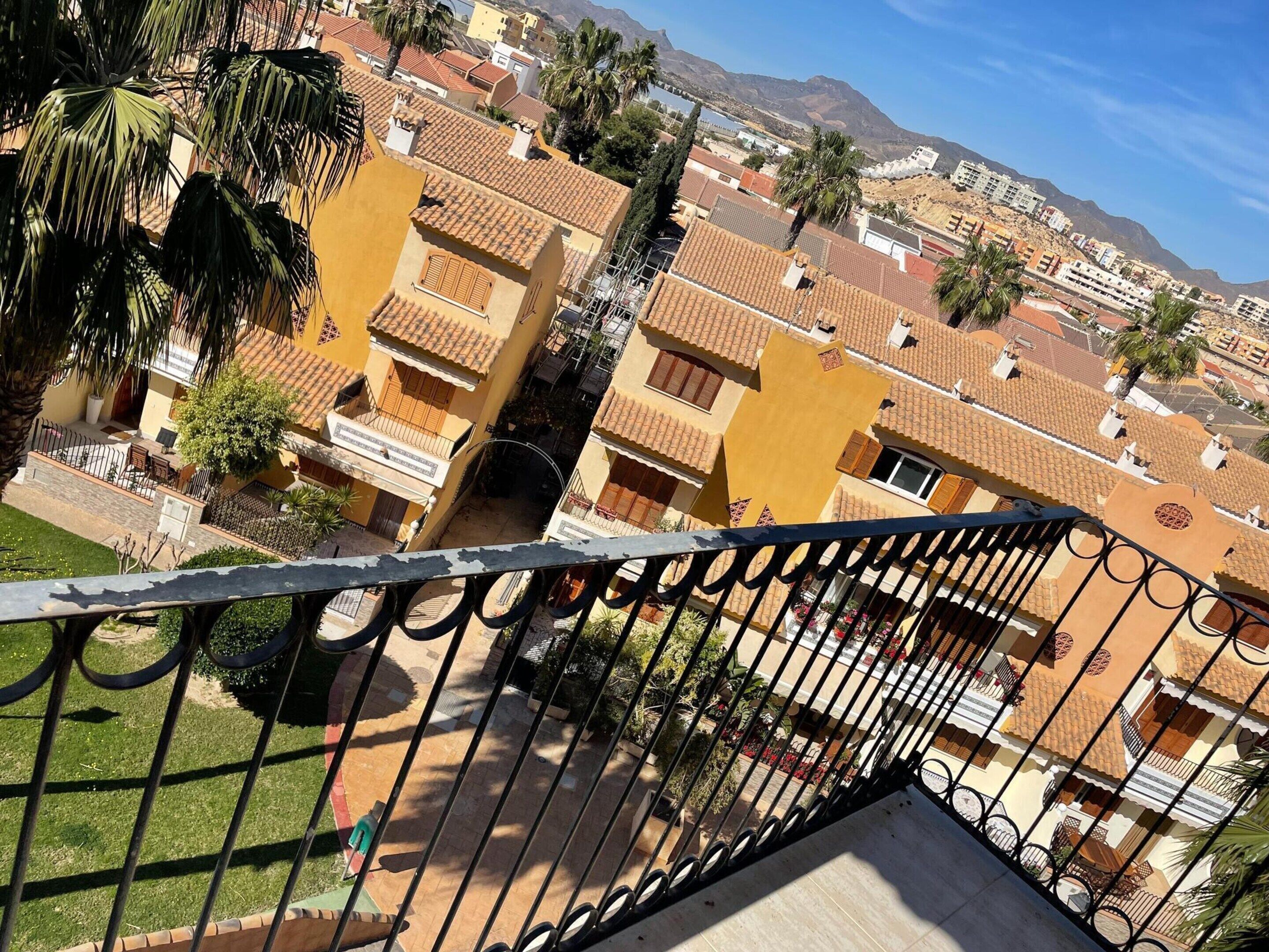 Zona residencial con edificios de tejados de teja y un balcón visible, con vistas despejadas del paisaje circundante.