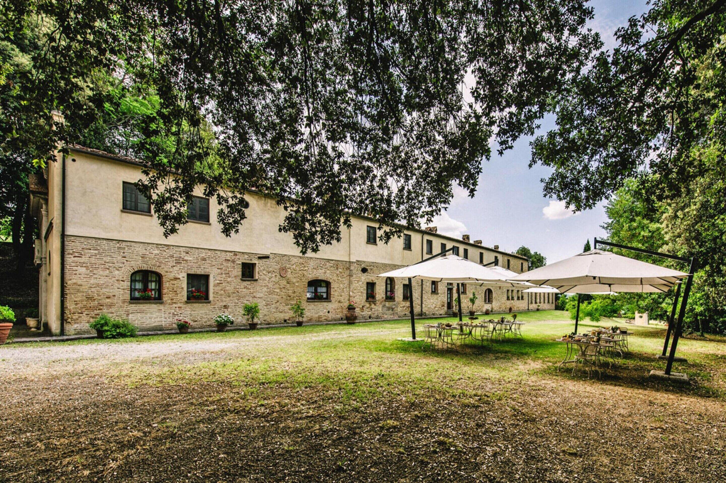 A courtyard with a building, outdoor tables, and umbrellas.