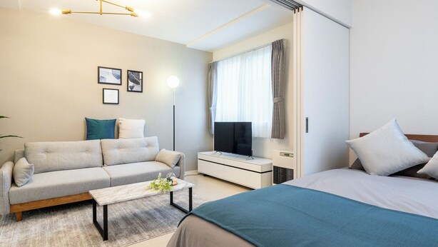 A modern hotel room with a bed, sofa, TV, and a desk. - UNAKITE 102 (Sapporo)