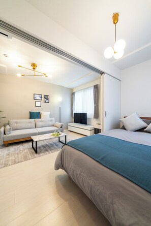 A modern hotel room with a bed, sofa, TV, and a desk. - UNAKITE 102 (Sapporo)