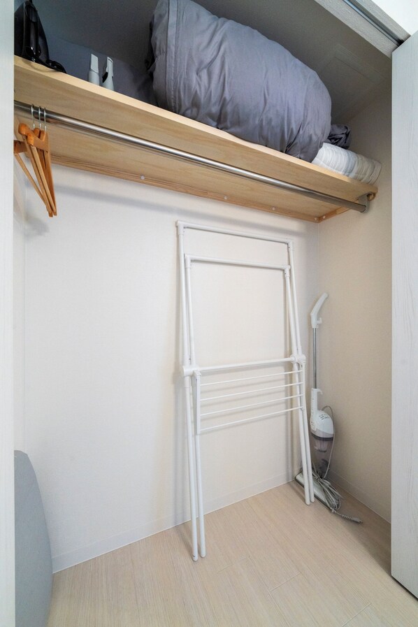 A compact room with a wooden shelf, a white drying rack, and a vacuum cleaner. - UNAKITE 102 (Sapporo)