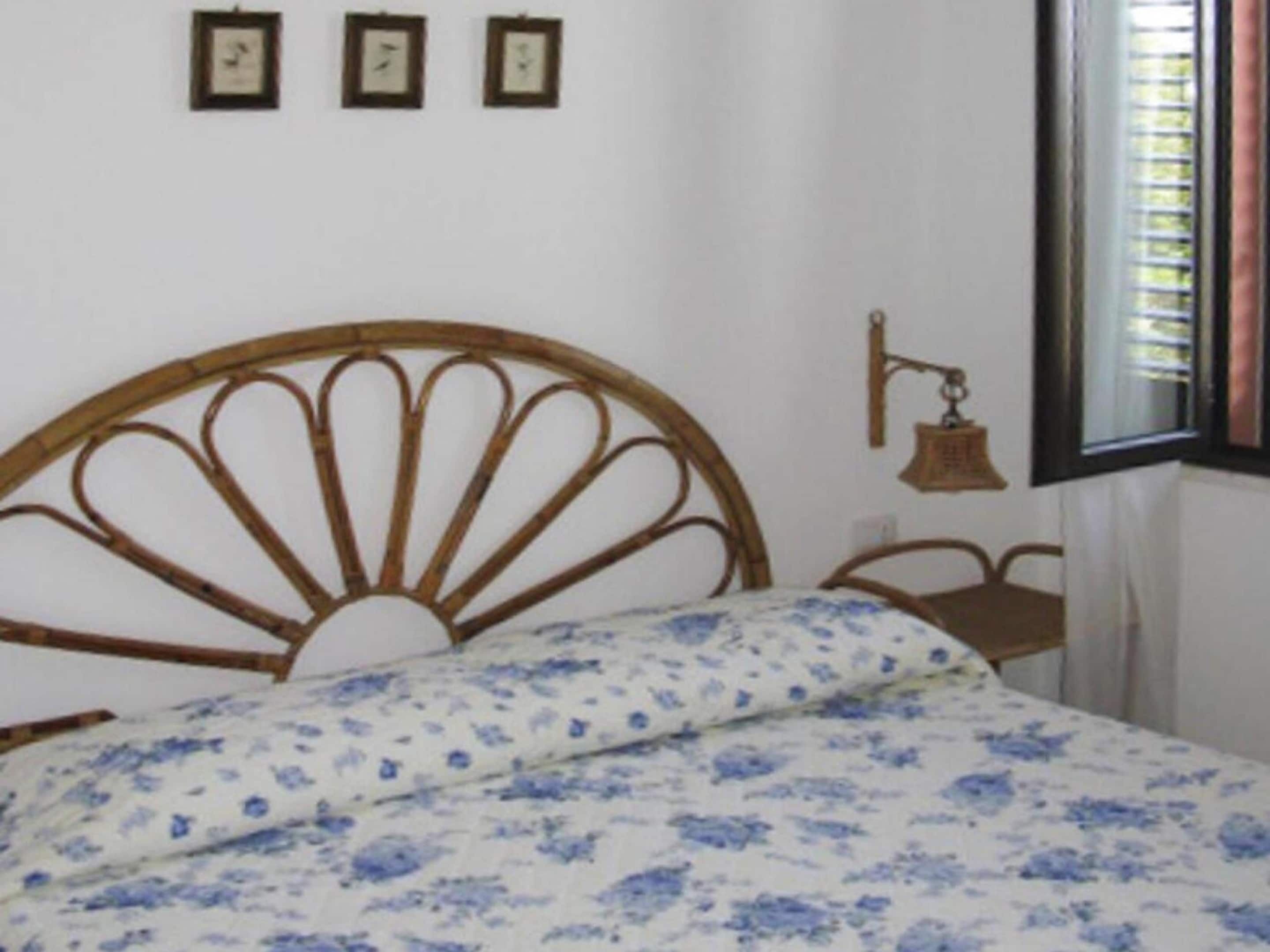 Ein Zimmer mit einem Bett, einem Fenster mit Jalousien und einer an der Wand befestigten Uhr.