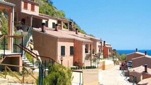 A coastal residential area with terraced houses, a clear sky, and a view of the sea. - Apartment in Costa Rei With Stunning Sea View (Muravera)