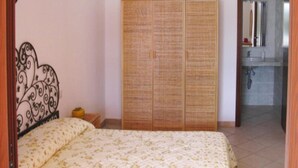 A bedroom with a bed, a wardrobe, and a bathroom visible through an open door. - Apartment in Costa Rei With Stunning Sea View (Muravera)