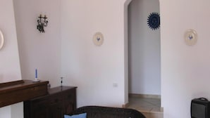 A living room with a sofa, a small table, a TV on a stand, and a staircase leading to another room. - Apartment in Costa Rei With Stunning Sea View (Muravera)