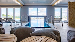 Amplio espacio interior con piscina, asientos y ventanas amplias que ofrecen vistas al exterior.