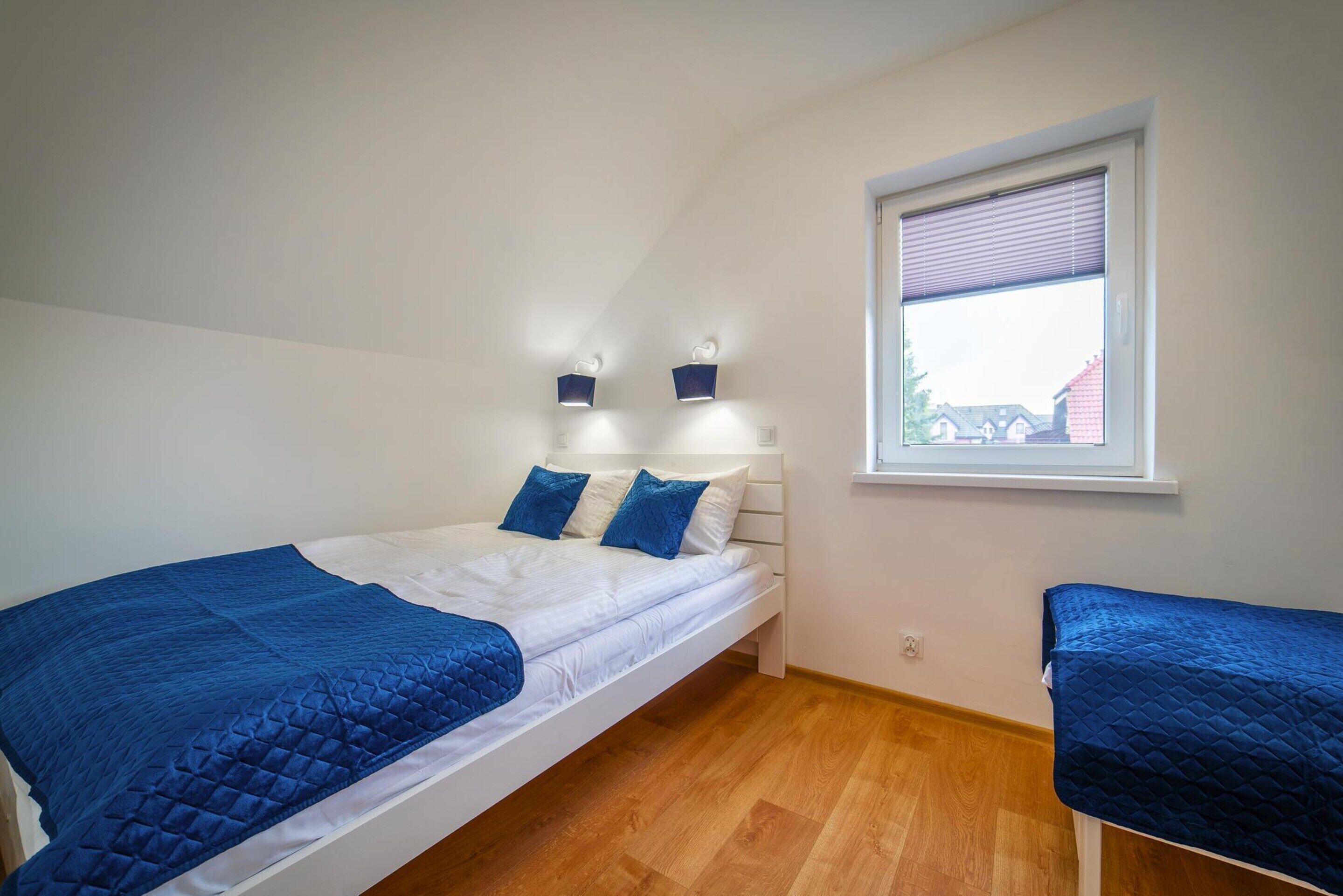 A bedroom with a single bed, a window with blinds, and two wall-mounted lights.