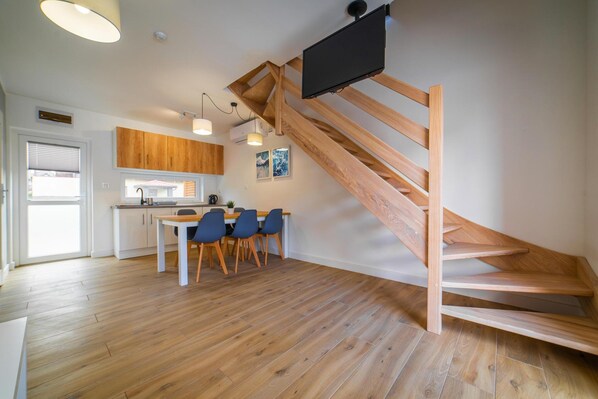 Une cuisine moderne avec des meubles en bois, un coin repas avec des chaises bleues et un escalier en bois.