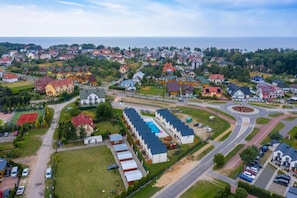 Et boligområde med enfamiliehuse og lejlighedskomplekser, en rundkørsel og en stor swimmingpool.
