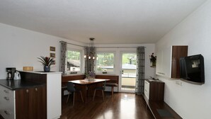 A compact kitchen with a dining area, wooden flooring, and a television mounted on the wall. - Apartment in Hippach Near Mayrhofen Ski Area (Hippach)
