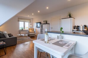 Un appartement moderne comprenant un coin repas, une cuisine et un salon.