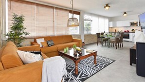 Un salon moderne comprenant un canapé, une table basse et un coin repas avec des chaises et une table.
