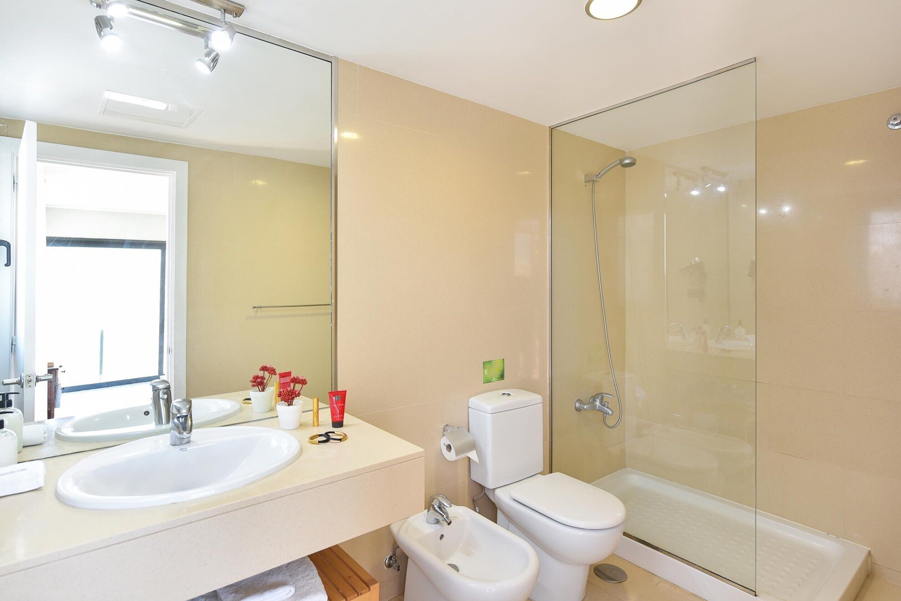 A modern bathroom with a large sink, toilet, and shower.