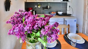 A kitchen with wooden cabinets, a microwave, and a sink. There is a vase with purple flowers on the counter. - Comfortable Holiday Homes With a Fireplace (Darlowo)