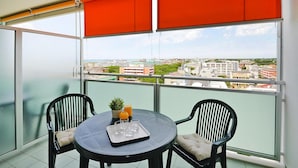 A balcony with two chairs and a table, a potted plant, and a tray with glasses and a candle. - Apartments Torre del Sole, Bibione Spiaggia (San Michele al Tagliamento)