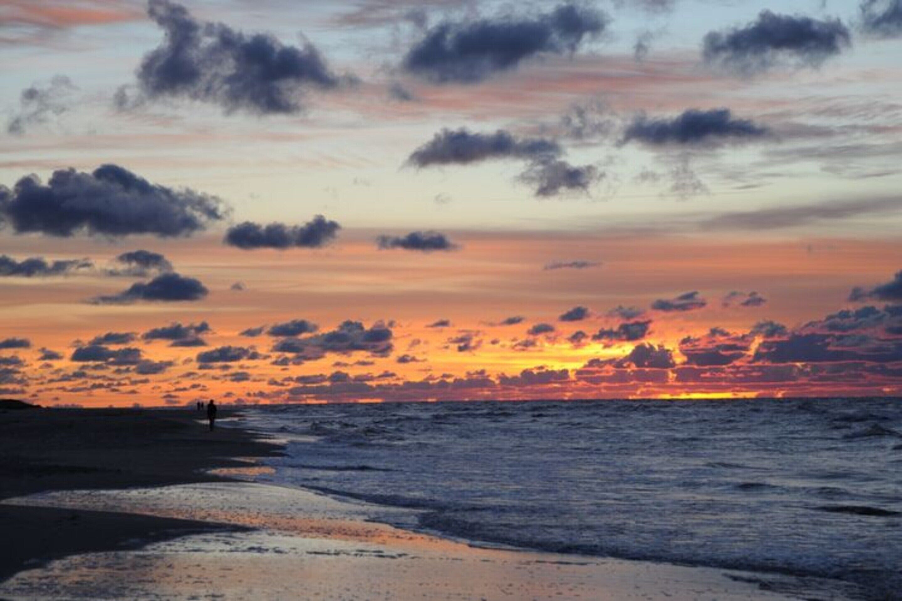 Spiaggia al tramonto con cielo sereno e onde oceaniche.