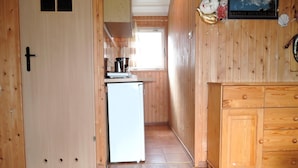Interior de madera con cocina, que incluye un refrigerador, armarios y una ventana.
