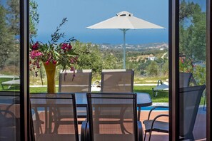 Eine Terrasse mit Tisch und Stühlen, eine Vase mit Blumen und Blick aufs Meer.