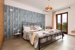 Ein Schlafzimmer mit Bett, Sessel, kleinem Tisch und Fenster mit Blick.