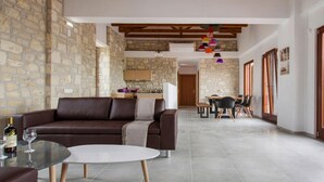 Una sala de estar moderna con un sofá de cuero marrón, una mesa de centro de vidrio y una zona de comedor con una mesa y sillas de madera.