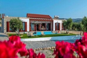 Ein modernes Haus mit Pool, Sitzgelegenheit im Freien und einer Steinaußenfassade.