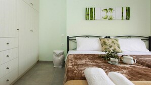 Un dormitorio ordenado con cama, mesita de noche con lámpara y una obra de arte en la pared.