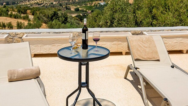 Terraza iluminada por el sol con una mesa dispuesta para dos, con vistas a un paisaje pintoresco.