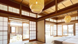A traditional Japanese room with tatami flooring, a low wooden table, and a bed with a futon. - Hayase House (Kure)