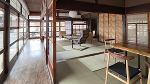A traditional Japanese room with tatami flooring, sliding doors, and a low table with chairs. - Hayase House (Kure)