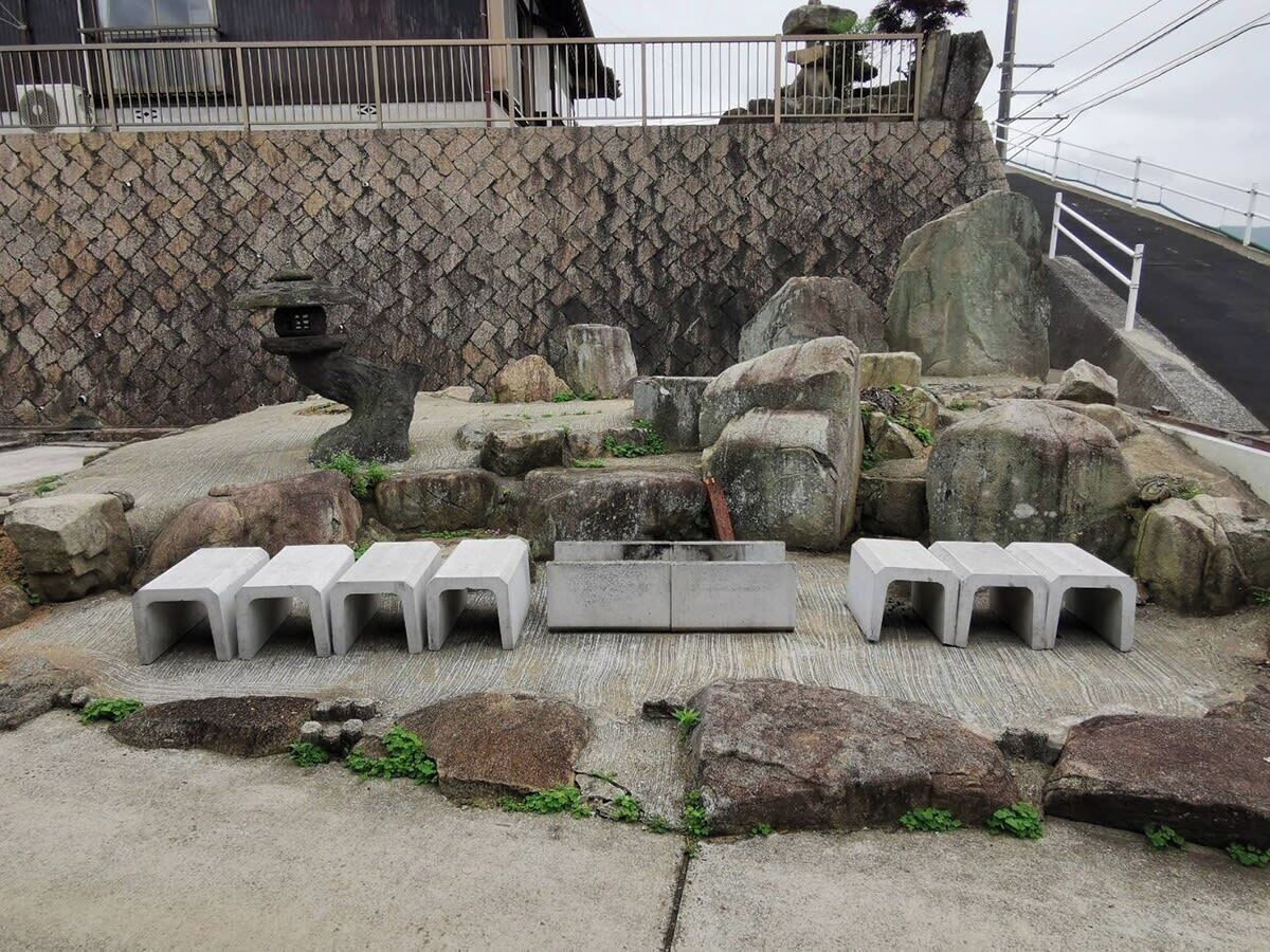 Un área de descanso de concreto con bancos y una estructura de piedra en un entorno rocoso.