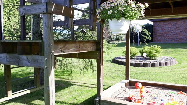 Una estructura de juego de madera con un arenero y juguetes.