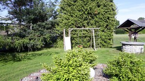 Un jardín con un columpio, un pabellón y un gran árbol.