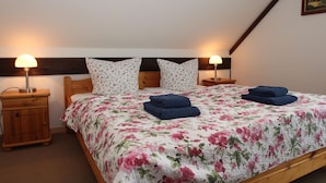 Une chambre à coucher avec un lit en bois, une literie à motifs floraux, deux lampes de chevet et une tête de lit en bois.
