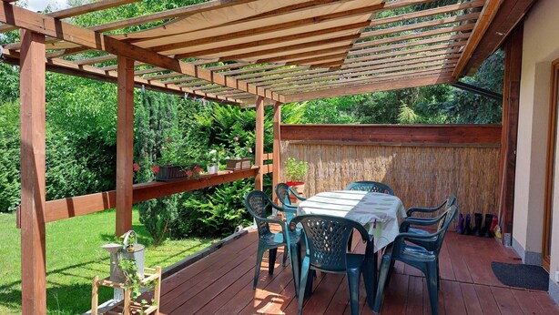 A wooden deck with a table and chairs, surrounded by lush greenery. - Appartment, Wieliczka by Cracow (Wieliczka)