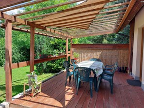 A wooden deck with a table and chairs, surrounded by lush greenery. - Appartment, Wieliczka by Cracow (Wieliczka)