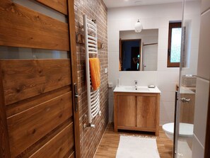 A modern bathroom with a wooden vanity, a white sink, and a glass shower enclosure. - Appartment, Wieliczka by Cracow (Wieliczka)