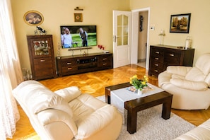 Una sala de estar con televisor, sofá, mesa de centro y aparador.