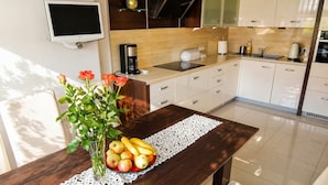 A modern kitchen with a dining table, a coffee maker, and a fruit bowl. - Terraced House Near Baltic Sea & Wolinski Park (Międzyzdroje)