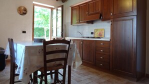 Una cocina con armarios de madera, una encimera blanca y una mesa de comedor con sillas.