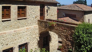Un edificio de piedra con tejado de tejas, un arco de piedra y un pequeño jardín con flores.