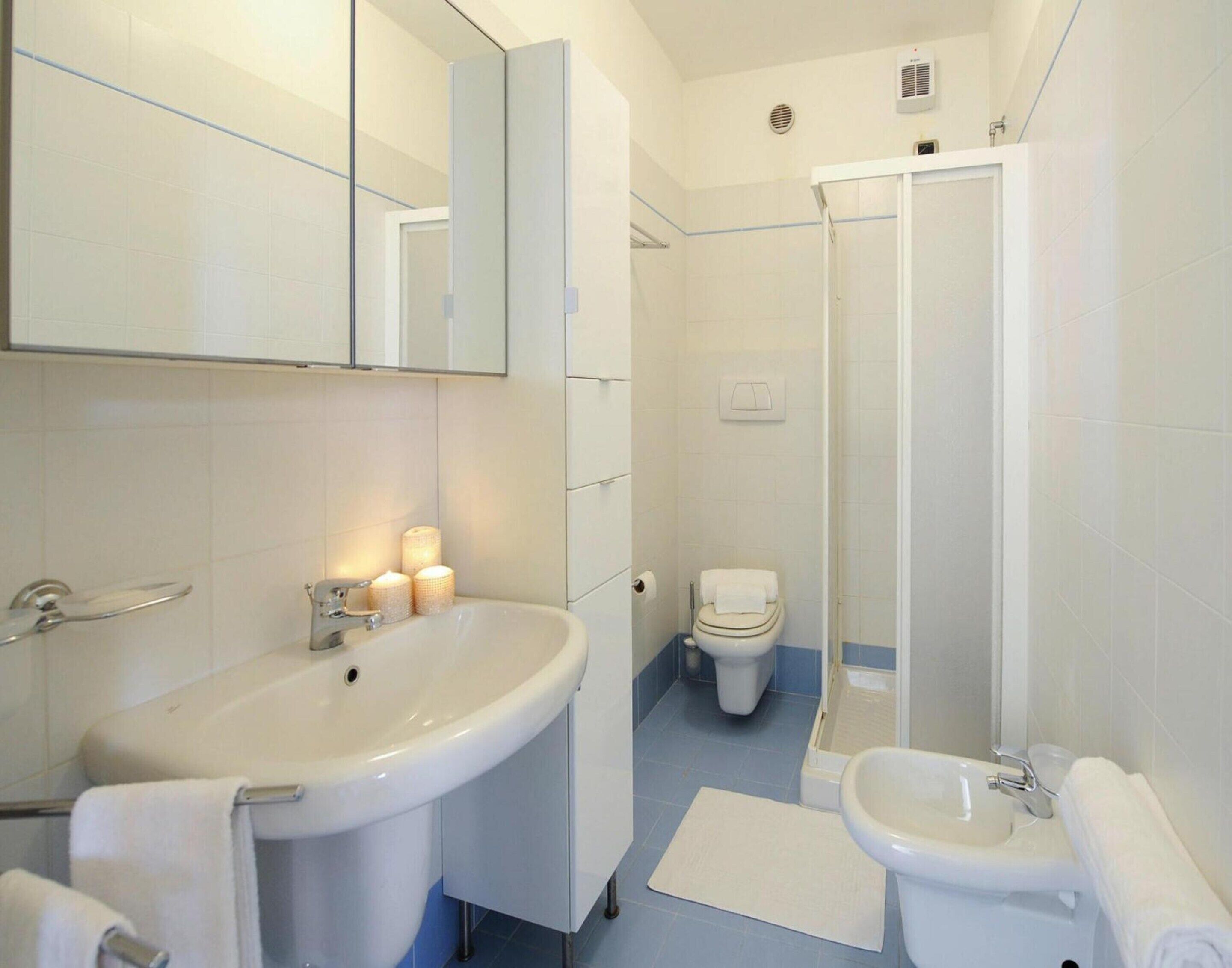A modern bathroom with a large sink, a bidet, and a shower area.
