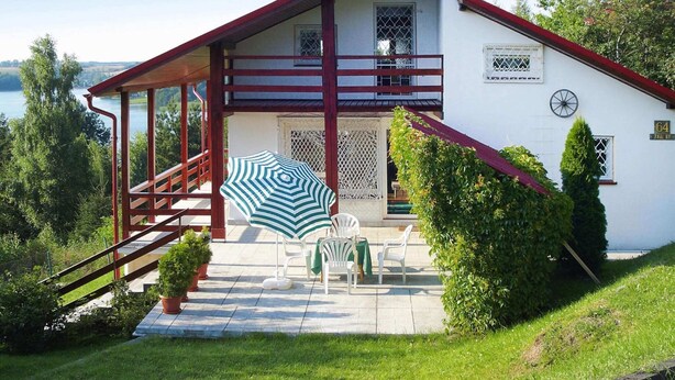 Een huis met twee verdiepingen, een balkon, een trap en een terras met tuinmeubilair.