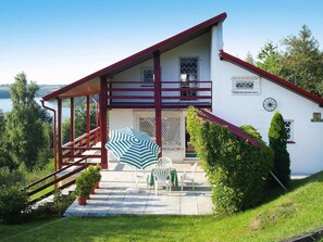 A two-story house with a balcony, a staircase, and a patio with outdoor furniture. - Beautiful Holiday Home in Zawory With Terrace (Chmielno)