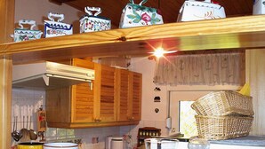 Een keuken met houten kastjes, een hanglamp en diverse keukenspullen op het aanrecht.