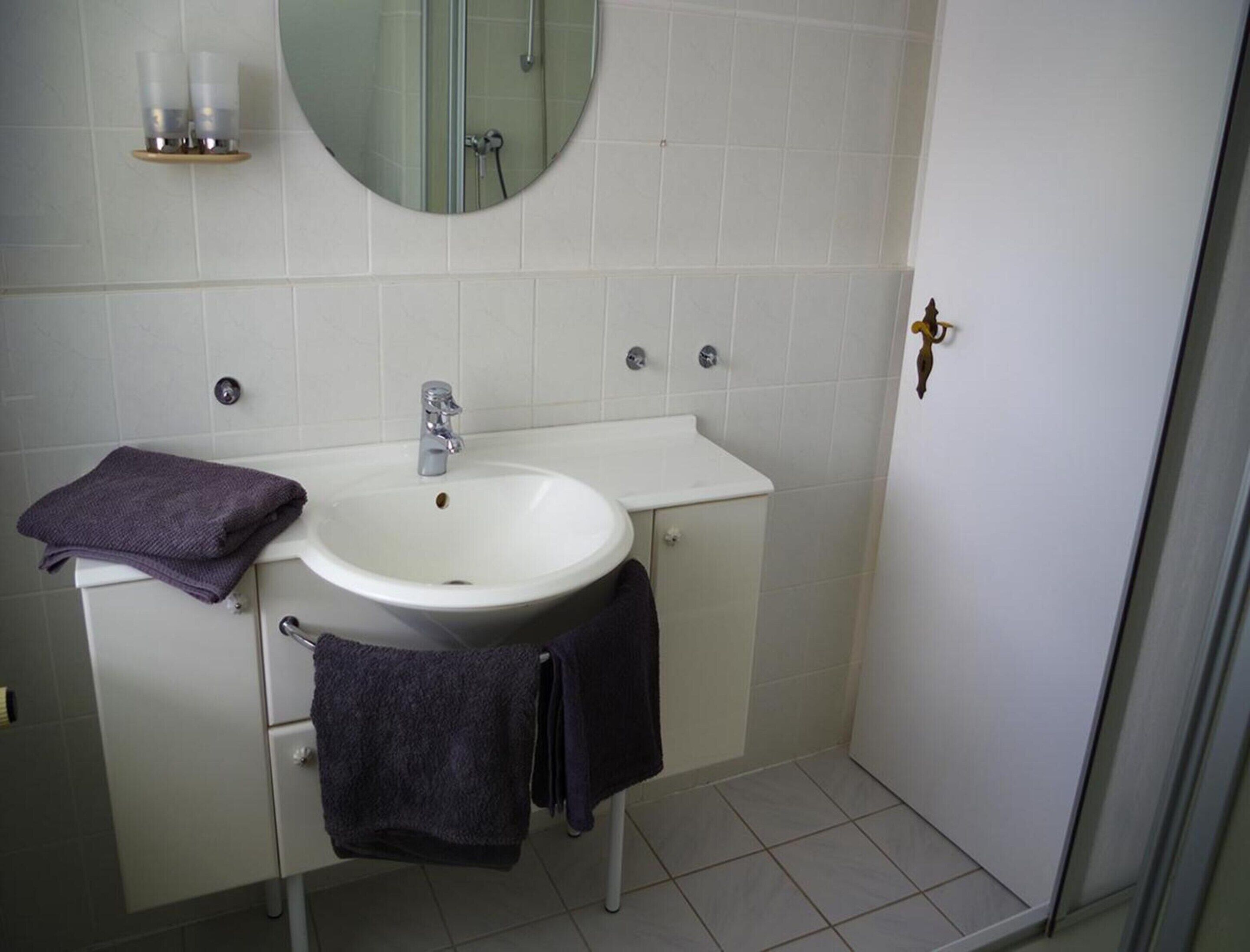 A bathroom with a white sink, mirror, and two towels.