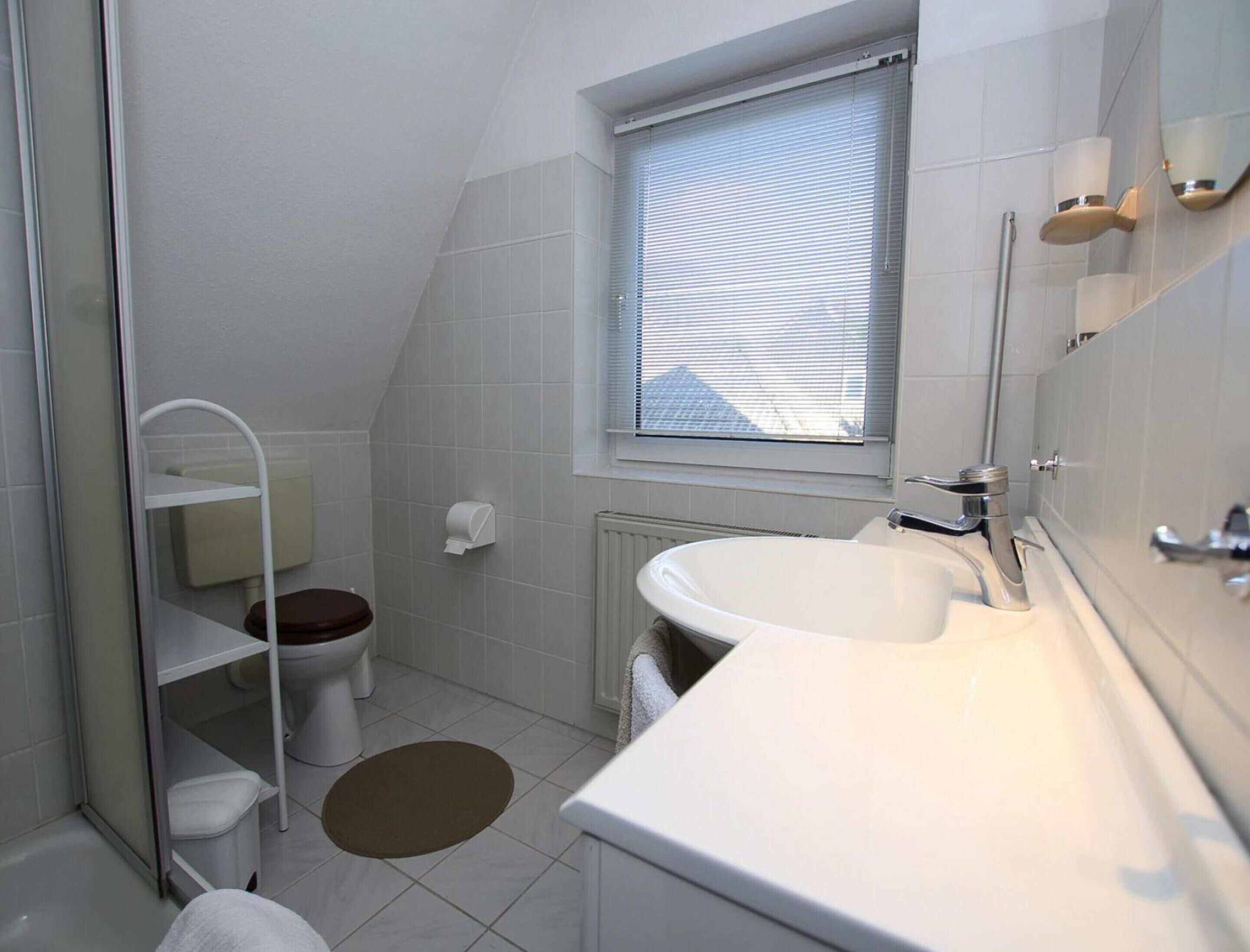A small, modern bathroom with a toilet, sink, and shower.