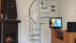 Una sala de estar con chimenea, televisor y un mueble de madera.