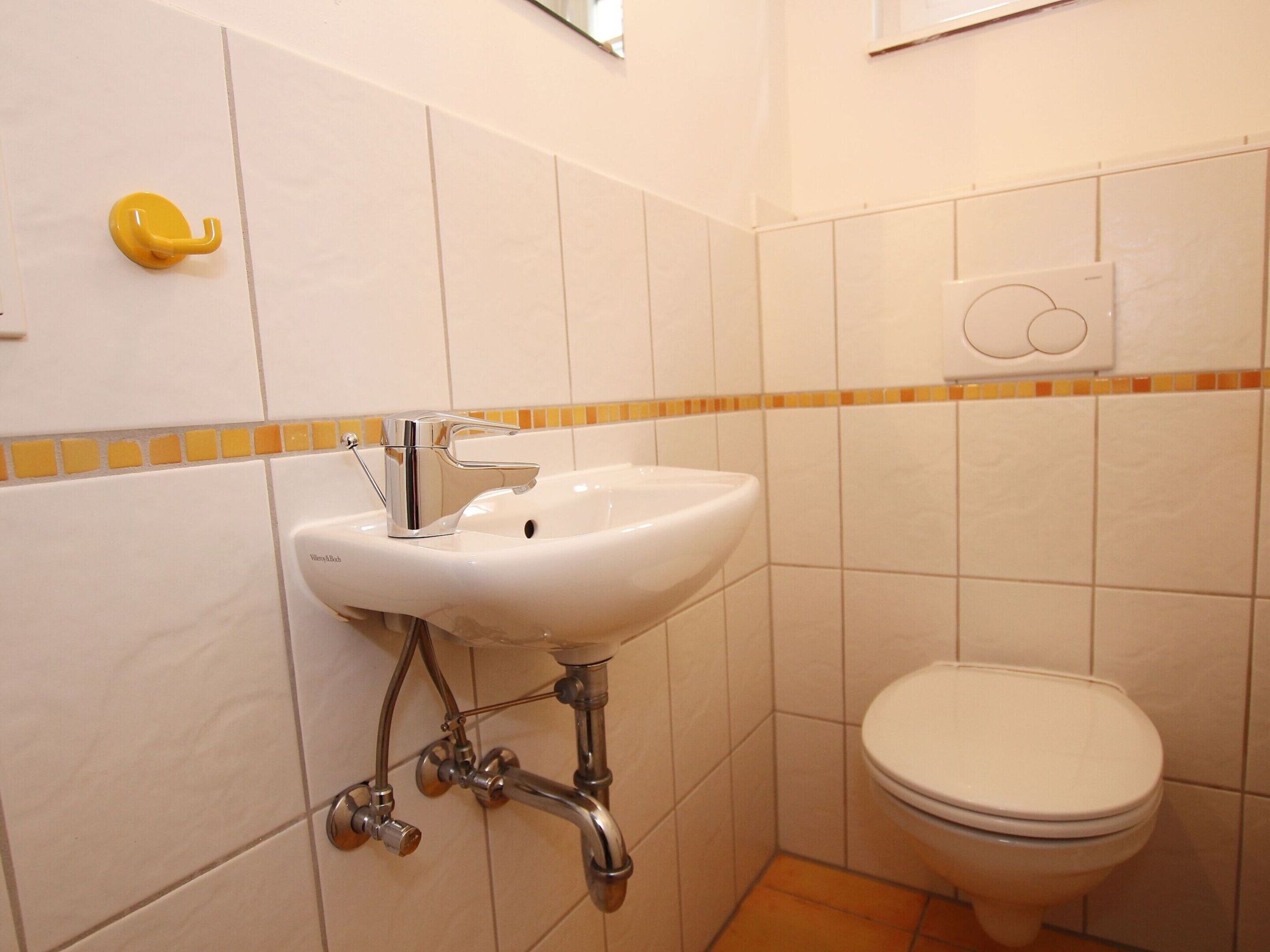 A bathroom with a white sink, chrome faucet, and a toilet.