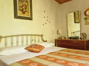 A bedroom with a bed, a dresser, a mirror, and a wall-mounted picture.